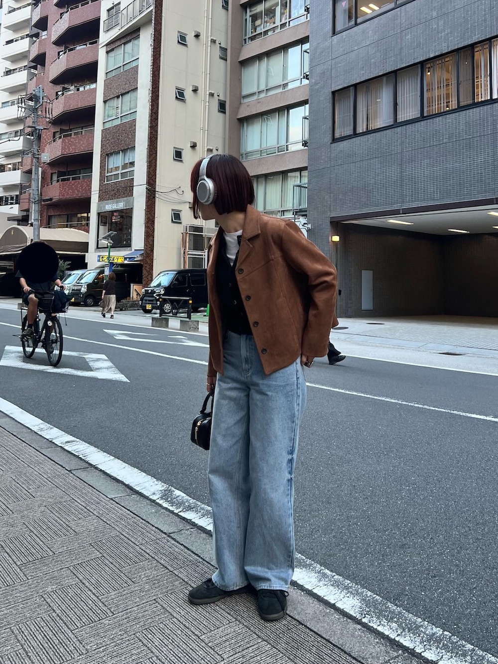 ブルー系のデニムパンツ、ブラック系のショルダーバッグ、ブラック系のカーディガン/ボレロを着用したレディースの秋コーディネートの2枚目の写真