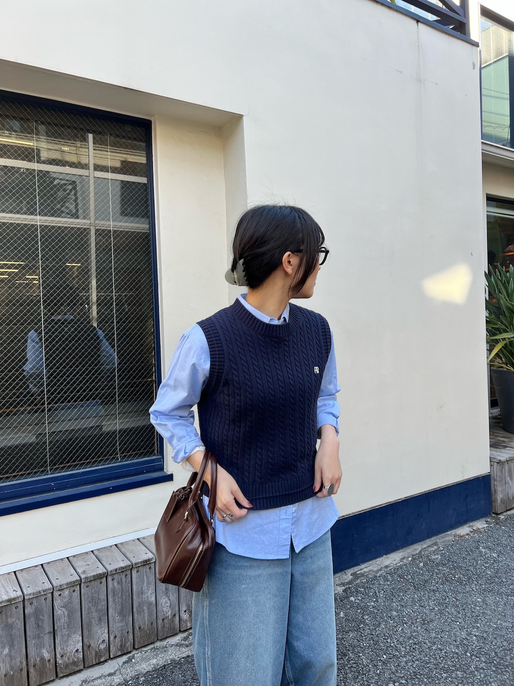 ブルー系のベスト、ブルー系のデニムパンツ、ブラウン系のハンドバッグを着用したレディースの冬コーディネートの3枚目の写真