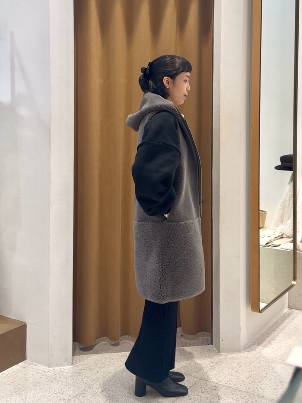 ブラック系のスウェット、グレー系のベスト、ブラック系のボストンバッグを着用したレディースの秋コーディネートの6枚目の写真