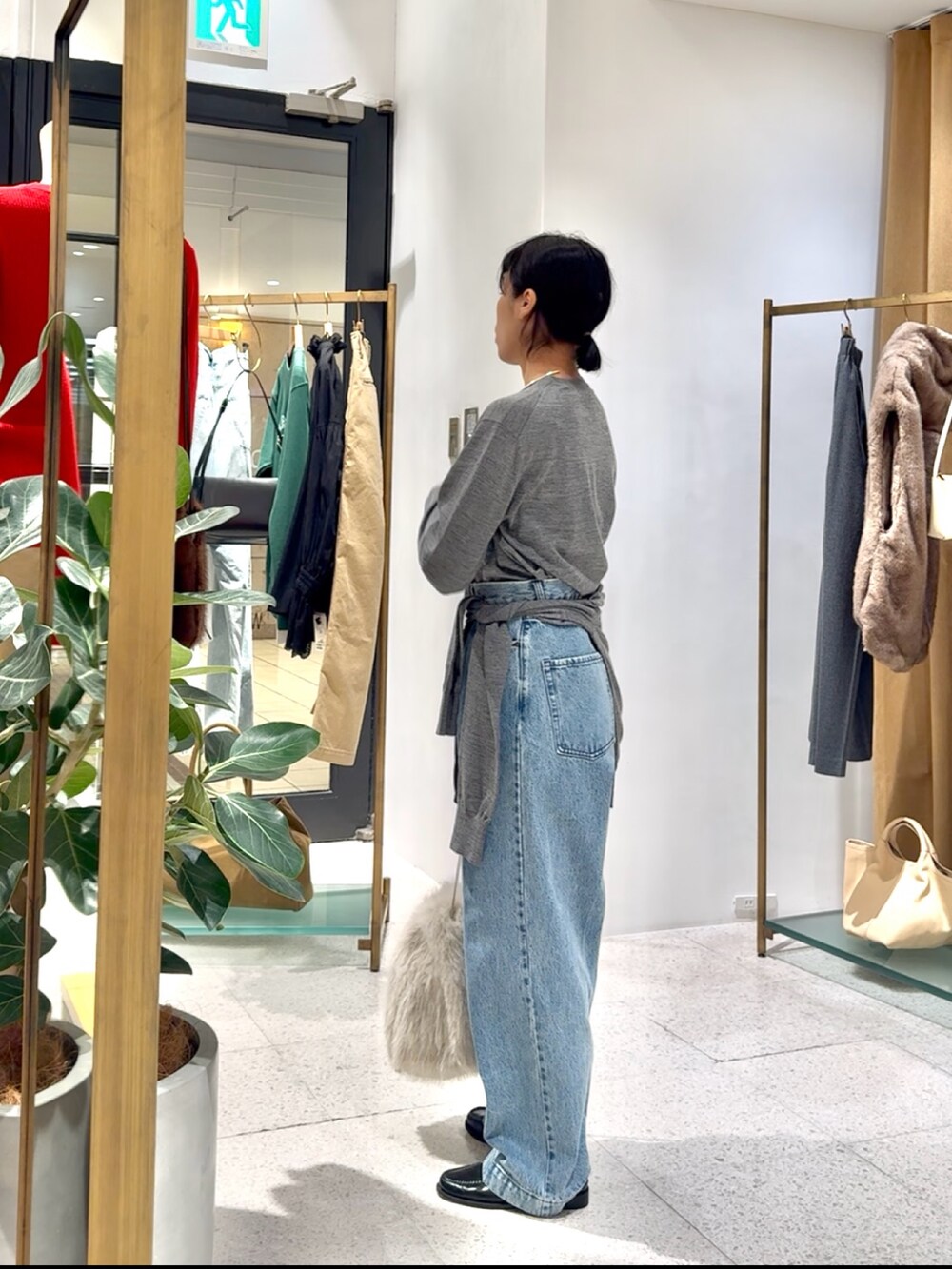 グレー系のカーディガン/ボレロ、グレー系のニット/セーター、ブルー系のデニムパンツを着用したレディースの秋コーディネートの6枚目の写真