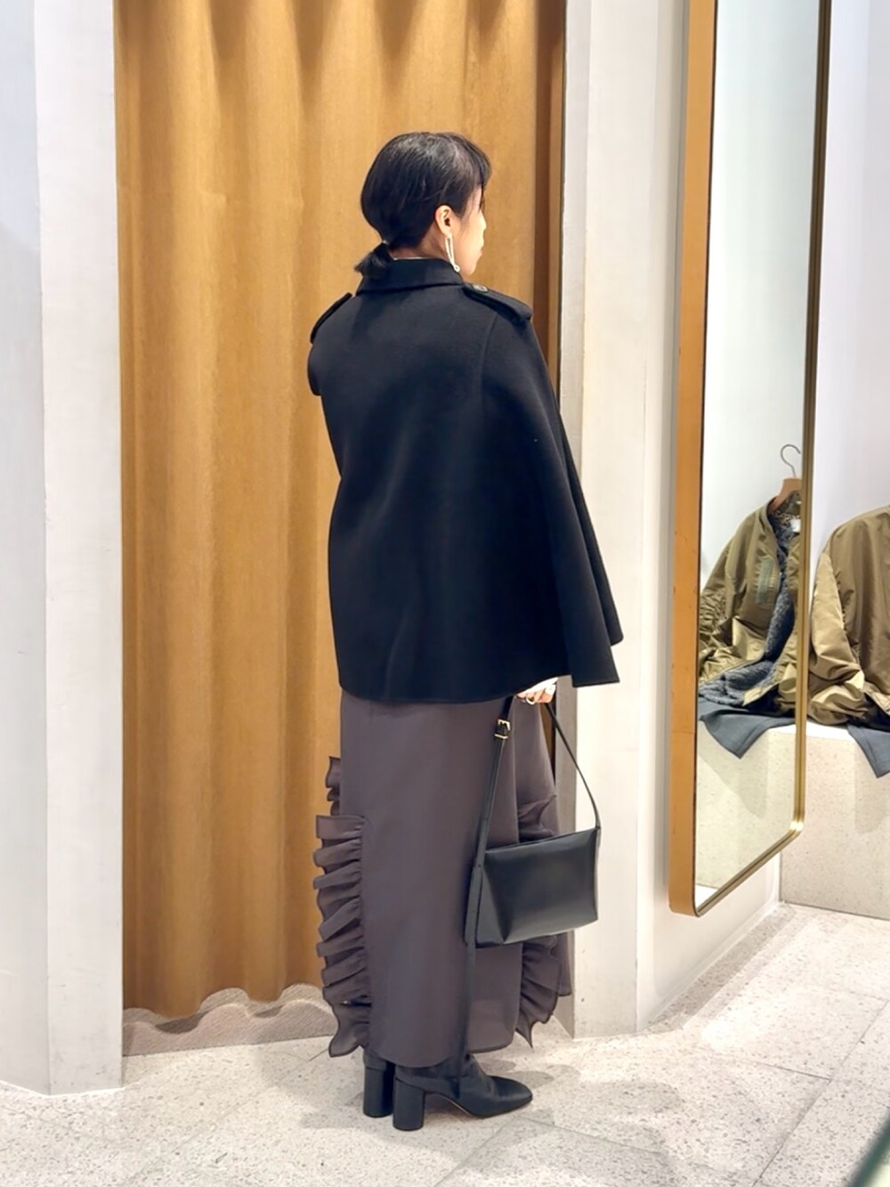 ブラック系のブーツ、ブラック系のショルダーバッグ、グレー系のワンピースを着用したレディースの秋コーディネートの3枚目の写真