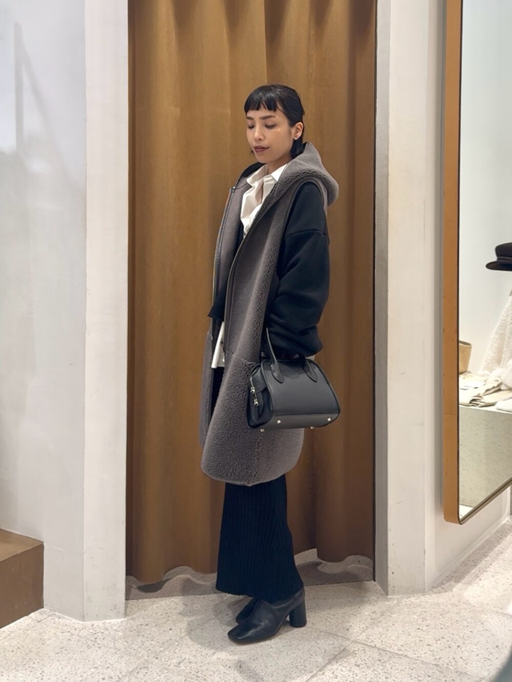 ブラック系のスウェット、グレー系のベスト、ブラック系のボストンバッグを着用したレディースの秋コーディネートの2枚目の写真