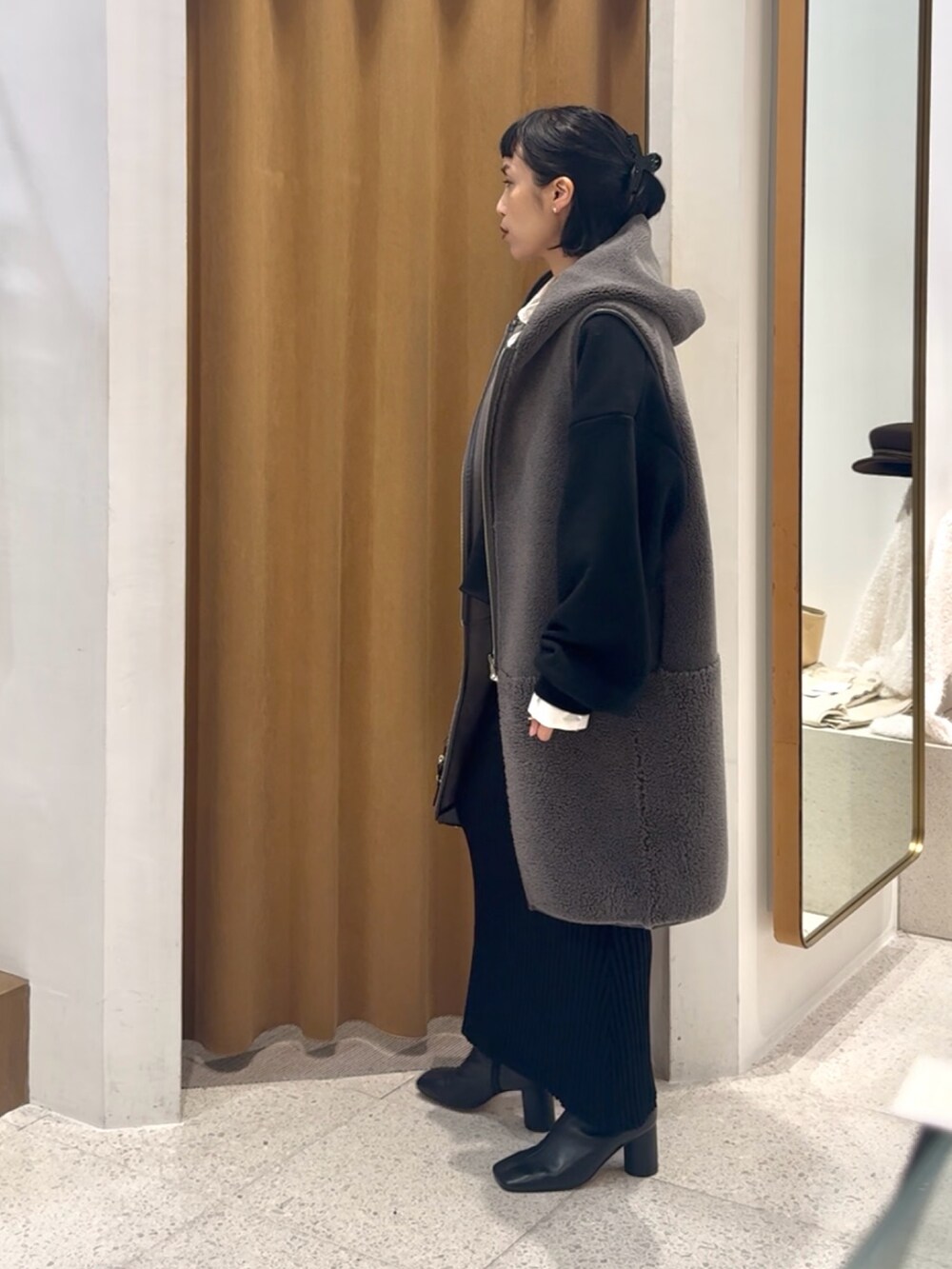 ブラック系のスウェット、グレー系のベスト、ブラック系のボストンバッグを着用したレディースの秋コーディネートの3枚目の写真