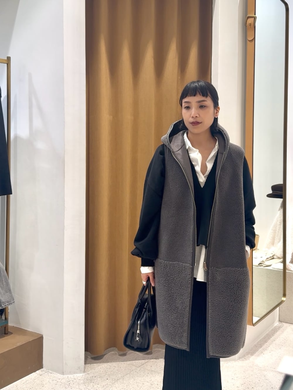 ブラック系のスウェット、グレー系のベスト、ブラック系のボストンバッグを着用したレディースの秋コーディネートの7枚目の写真