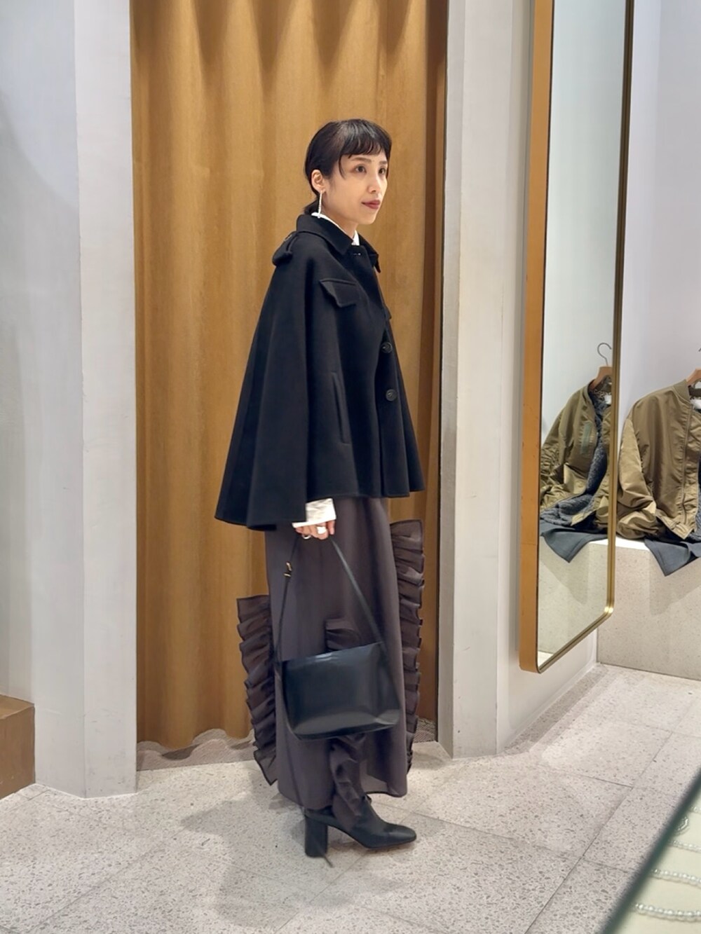 ブラック系のブーツ、ブラック系のショルダーバッグ、グレー系のワンピースを着用したレディースの秋コーディネートの2枚目の写真