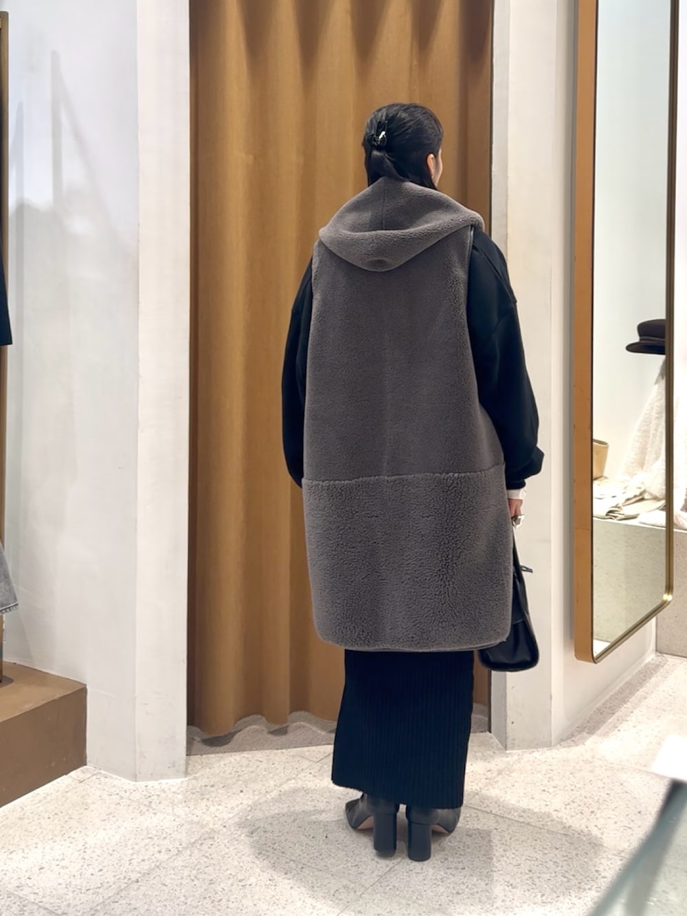 ブラック系のスウェット、グレー系のベスト、ブラック系のボストンバッグを着用したレディースの秋コーディネートの5枚目の写真