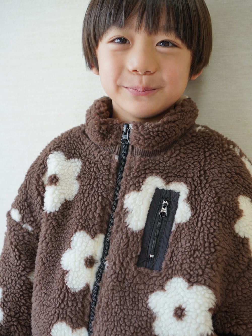 レッド系のチノパンツ、ブラック系のスニーカー、ブラウン系のブルゾンを着用したキッズの冬コーディネートの4枚目の写真