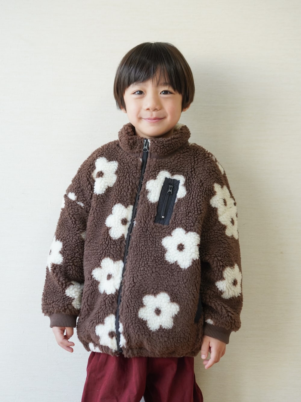 レッド系のチノパンツ、ブラック系のスニーカー、ブラウン系のブルゾンを着用したキッズの冬コーディネートの2枚目の写真