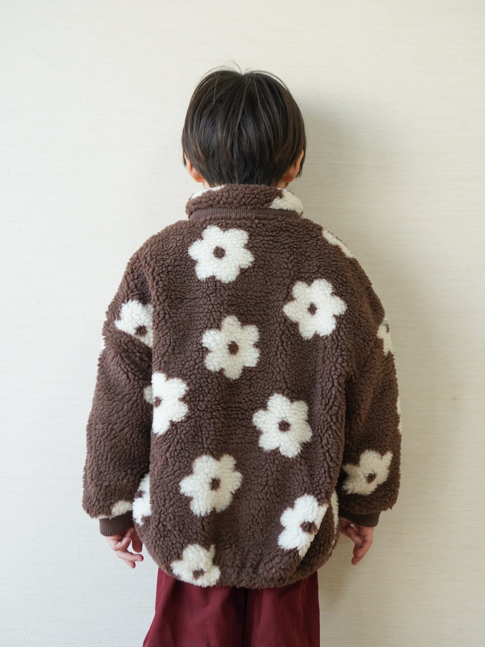 レッド系のチノパンツ、ブラック系のスニーカー、ブラウン系のブルゾンを着用したキッズの冬コーディネートの3枚目の写真