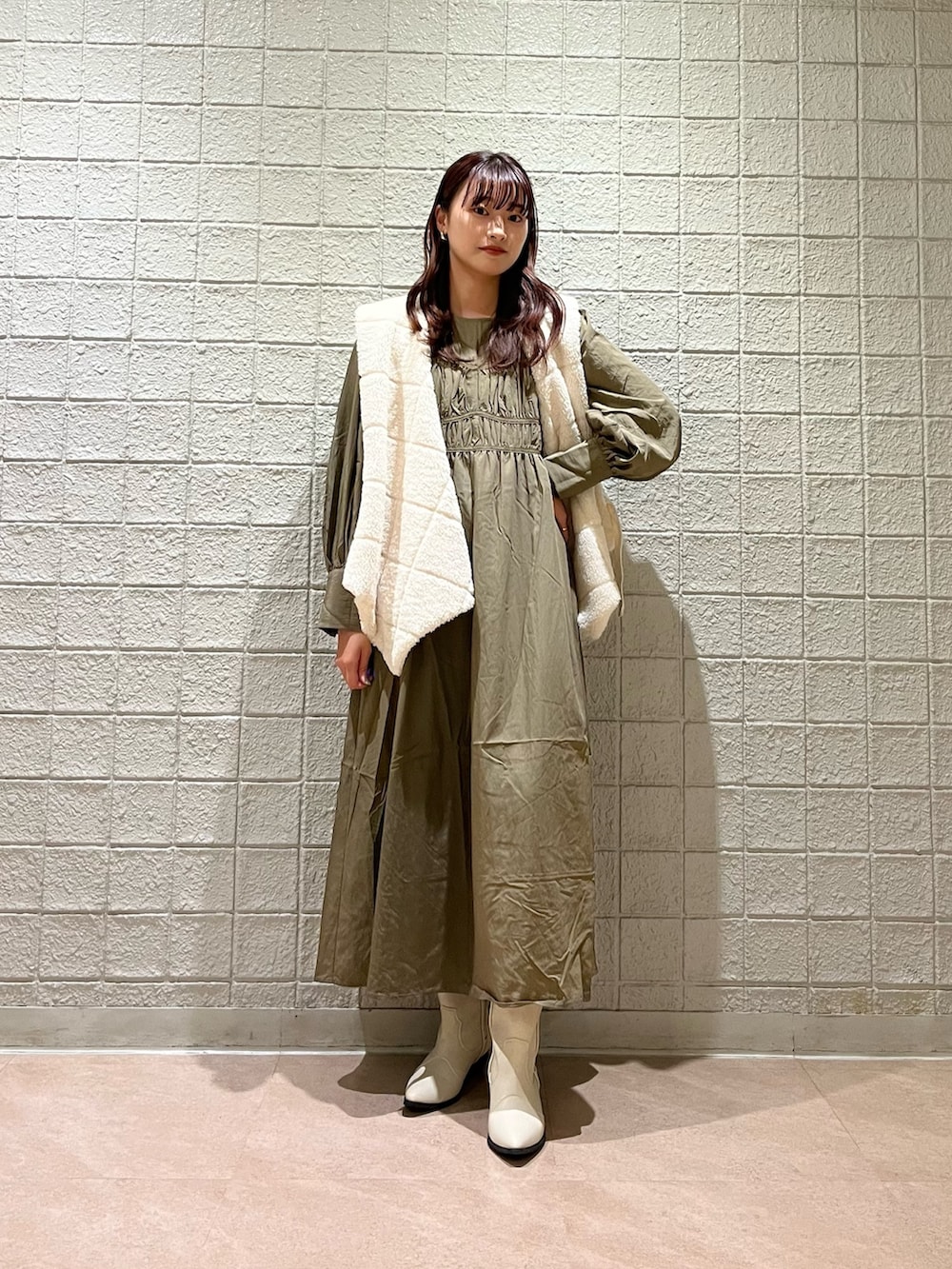 ブラウン系のワンピース、ホワイト系のベスト、ホワイト系のブーツを着用したレディースの春コーディネートの2枚目の写真