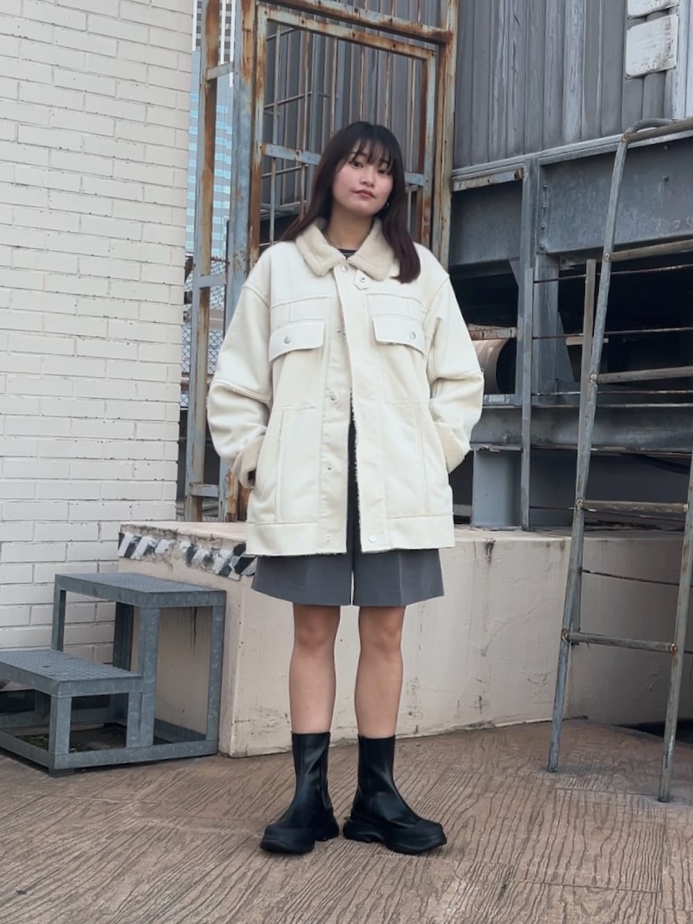 ホワイト系のその他アウター、グレー系のその他パンツ、ブラック系のブーツを着用したレディースの冬コーディネートの2枚目の写真