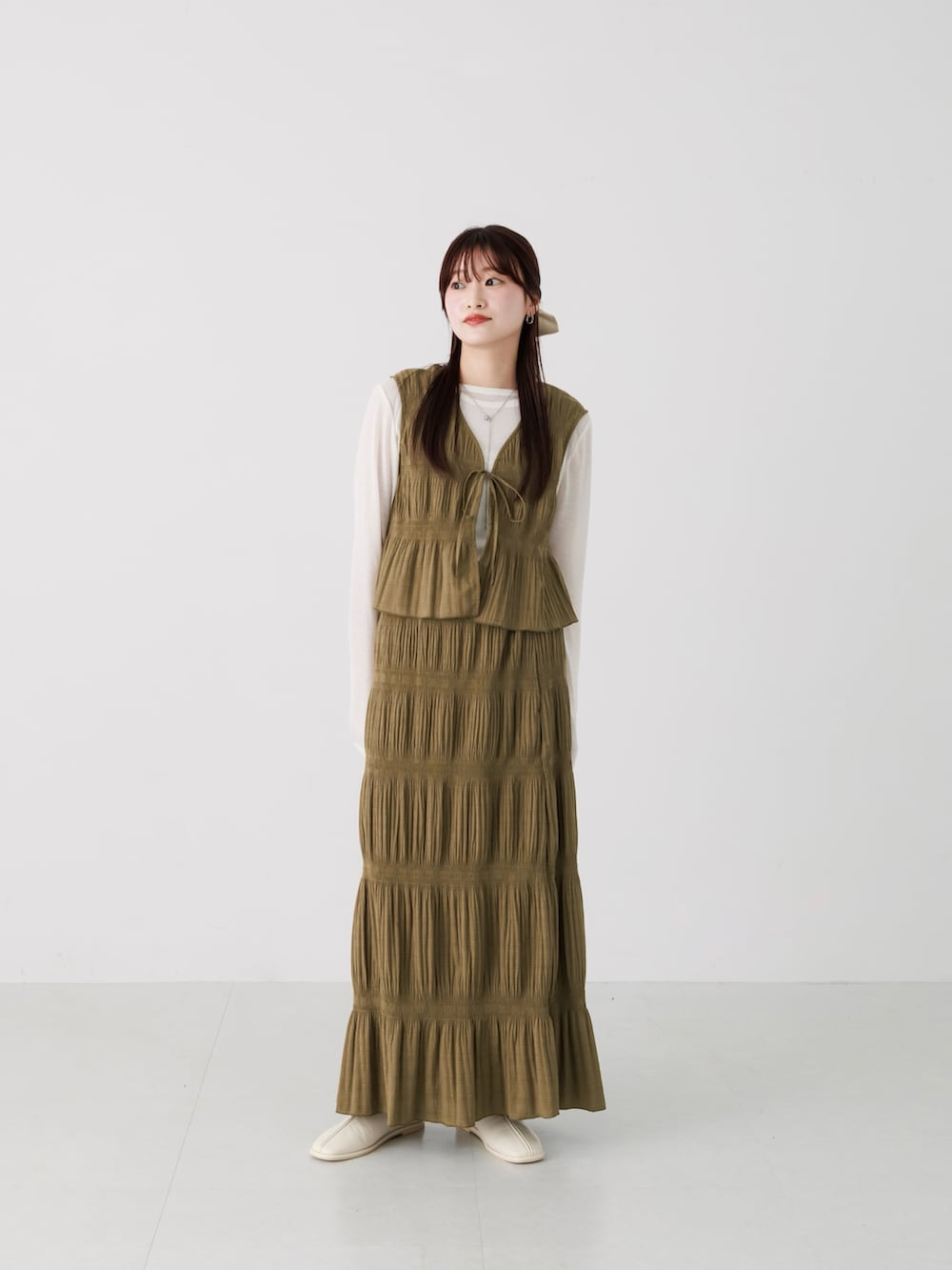 グリーン系のセットアップ、ホワイト系のTシャツ/カットソー、ホワイト系のパンプスを着用したレディースの冬コーディネートの2枚目の写真