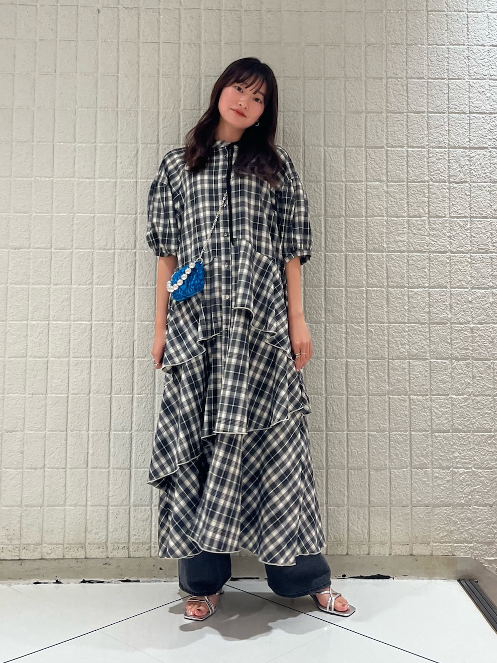 ブラック系のワンピース、ブルー系のショルダーバッグ、ブラック系のデニムパンツを着用したレディースの冬コーディネートの2枚目の写真