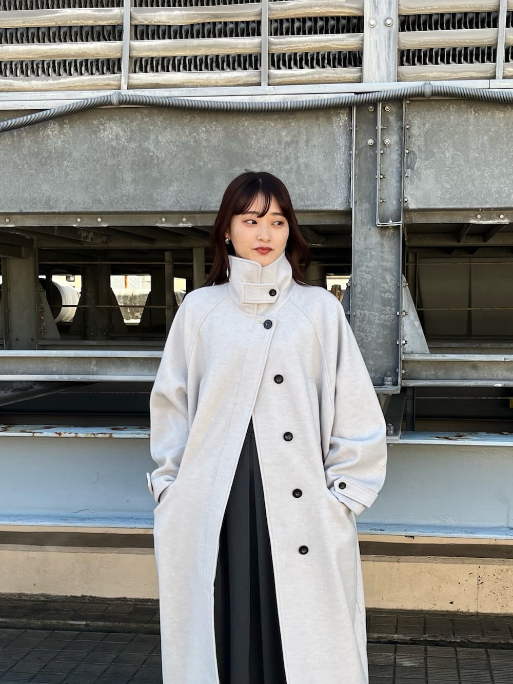 グレー系のステンカラーコート、グレー系のワンピース、ホワイト系のブーツを着用したレディースの春コーディネートの3枚目の写真