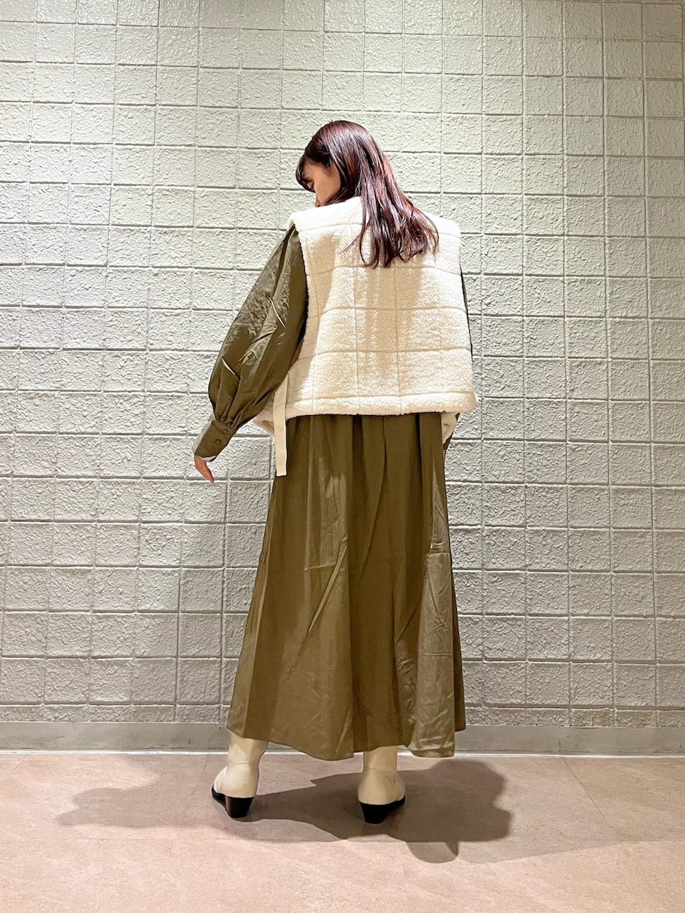 ブラウン系のワンピース、ホワイト系のベスト、ホワイト系のブーツを着用したレディースの春コーディネートの3枚目の写真