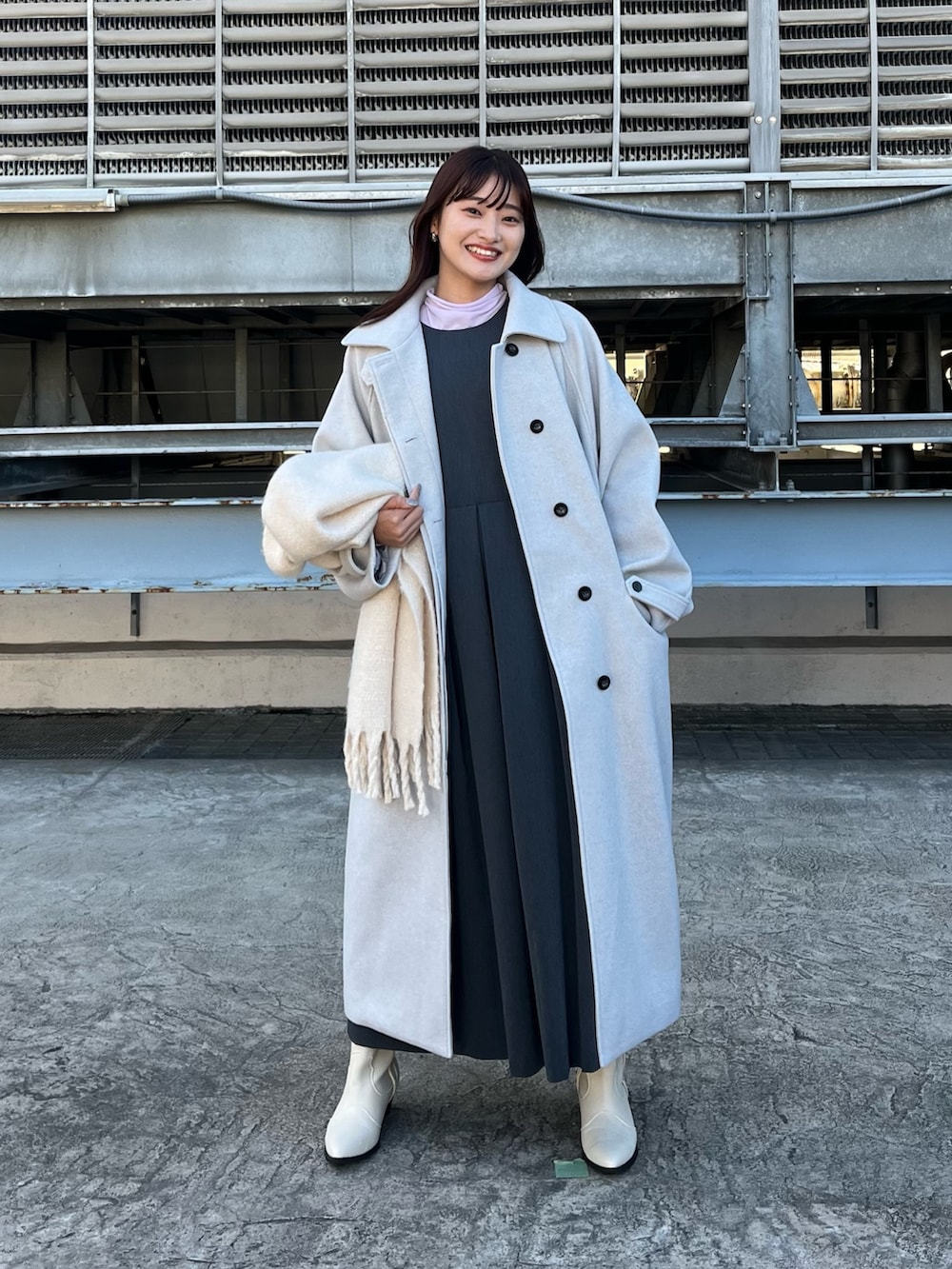 グレー系のステンカラーコート、グレー系のワンピース、ホワイト系のブーツを着用したレディースの春コーディネートの2枚目の写真