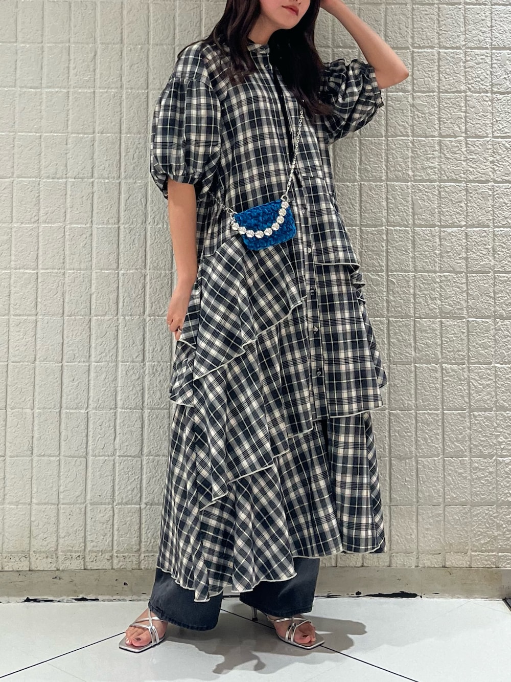 ブラック系のワンピース、ブルー系のショルダーバッグ、ブラック系のデニムパンツを着用したレディースの冬コーディネートの3枚目の写真