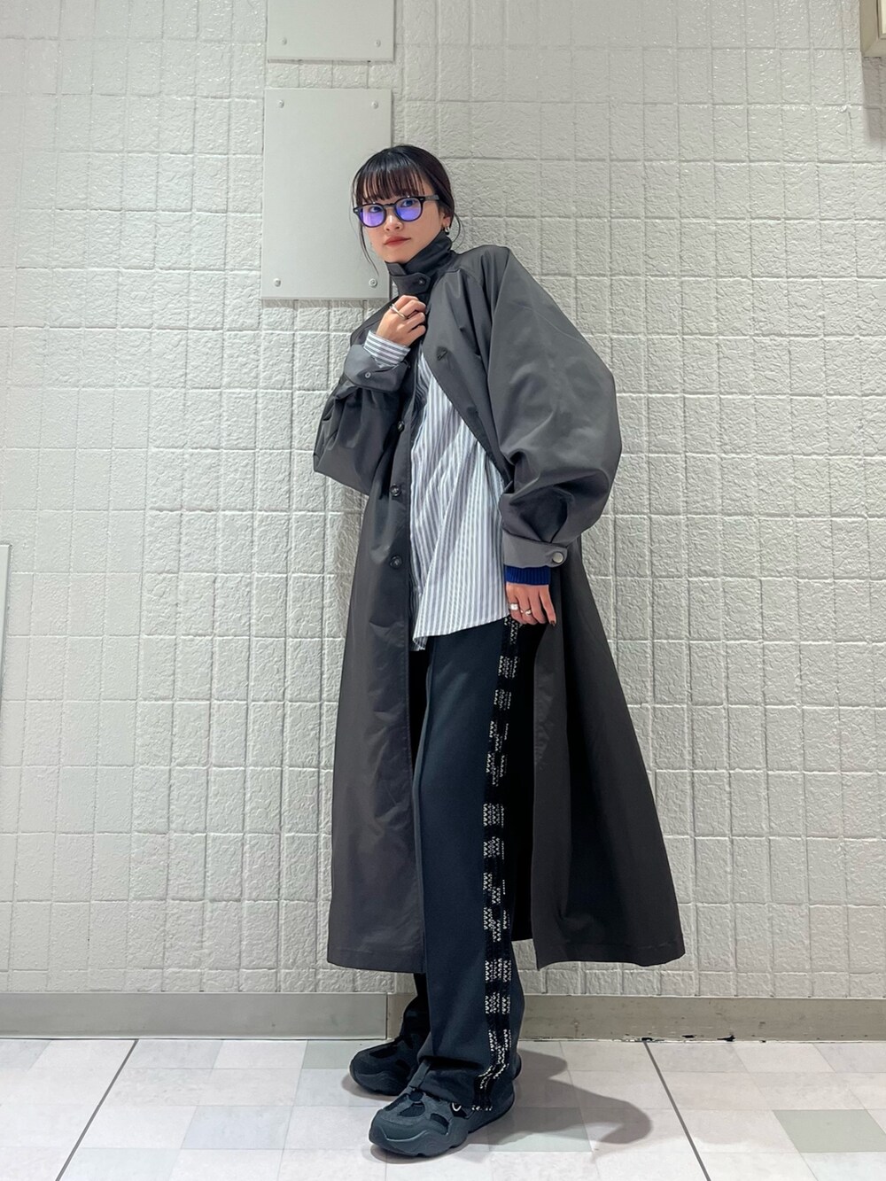 グレー系のステンカラーコート、ホワイト系のシャツ/ブラウス、グレー系のその他パンツを着用したレディースの春コーディネートの2枚目の写真