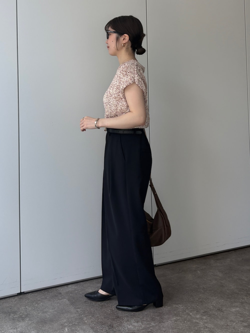 ピンク系のニット/セーター、ブラック系のスラックス、ブラック系のパンプスを着用したレディースの春コーディネートの2枚目の写真