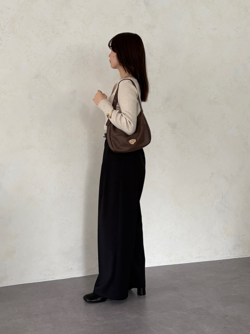 ブラック系のスラックス、ホワイト系のニット/セーター、ブラウン系のトートバッグを着用したレディースの秋コーディネートの2枚目の写真