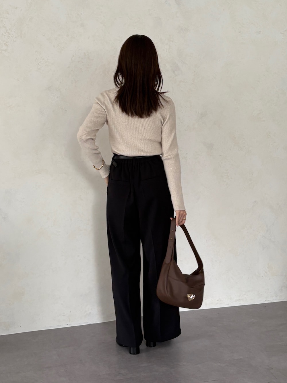 ブラック系のスラックス、ホワイト系のニット/セーター、ブラウン系のトートバッグを着用したレディースの秋コーディネートの3枚目の写真
