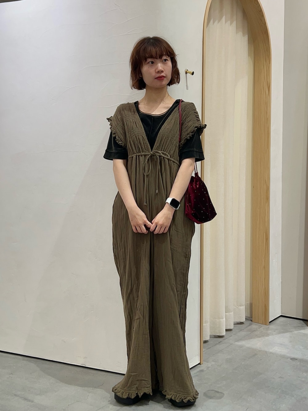 グリーン系のサロペット/オーバーオール、レッド系のトートバッグ、ブラック系のTシャツ/カットソーを着用したレディースの秋コーディネートの2枚目の写真
