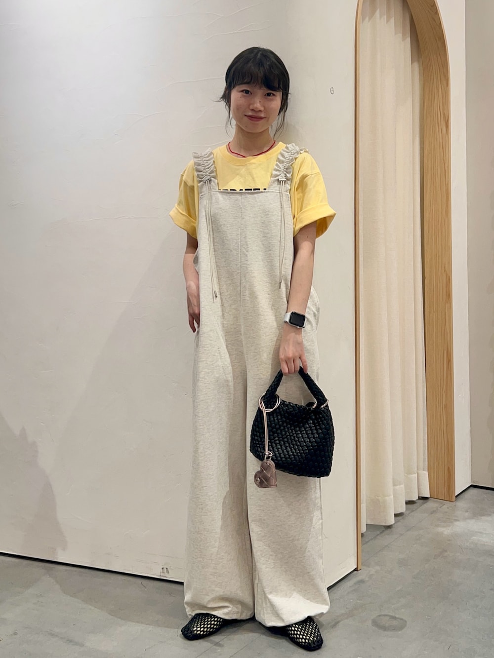 イエロー系のTシャツ/カットソー、ホワイト系のつなぎ/オールインワン、ブラック系のショルダーバッグを着用したレディースの夏コーディネートの2枚目の写真