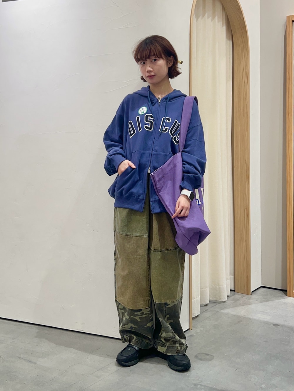 ブルー系のパーカー、パープル系のトートバッグ、グリーン系のその他パンツを着用したレディースの秋コーディネートの2枚目の写真