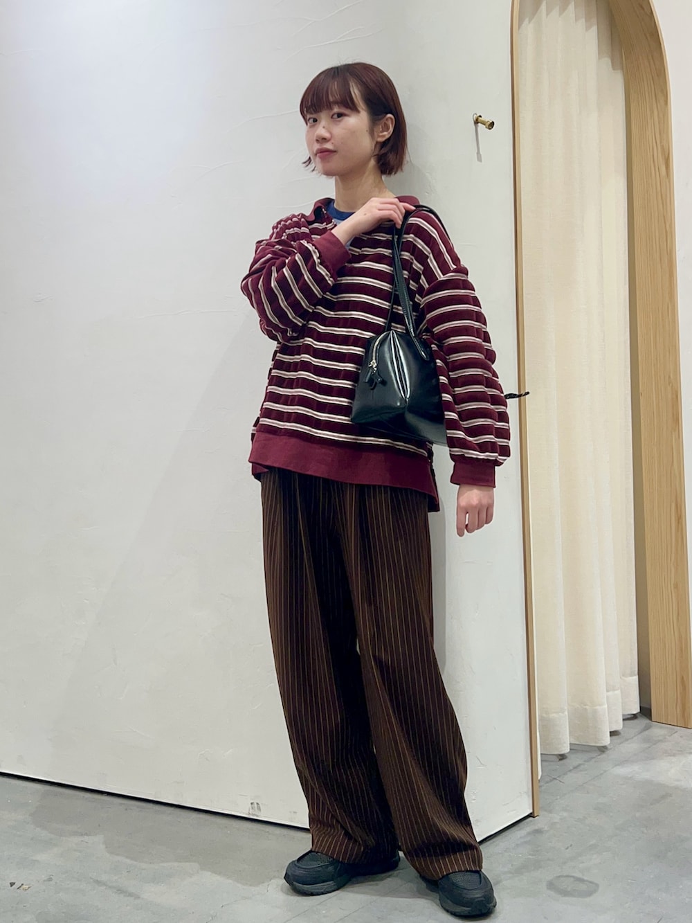 レッド系のTシャツ/カットソー、ブラウン系のスラックス、ブラック系のトートバッグを着用したレディースの冬コーディネートの2枚目の写真