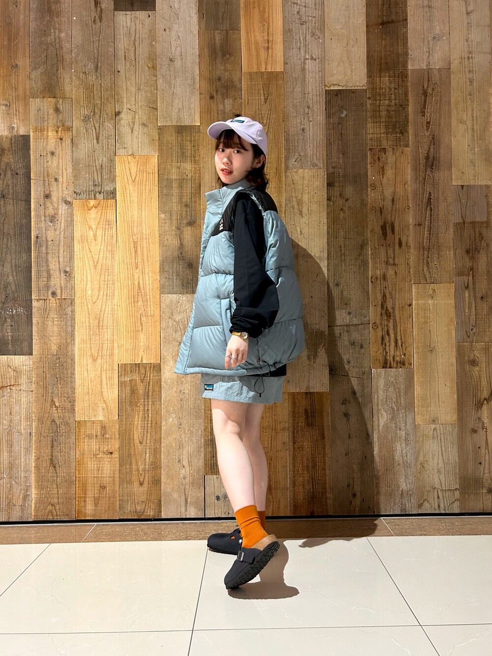 ブラック系のTシャツ/カットソー、ブルー系のダウンベスト、ベージュ系のその他パンツを着用したレディースの秋コーディネートの2枚目の写真