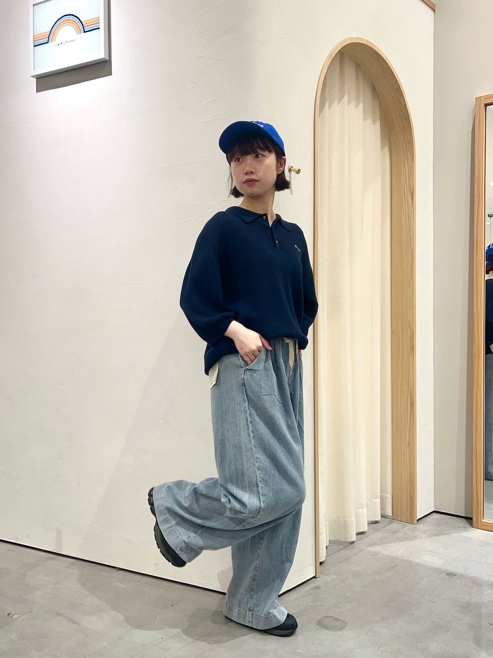 ブルー系のニット/セーター、ブルー系のデニムパンツ、ブルー系のキャップを着用したレディースの春コーディネートの2枚目の写真