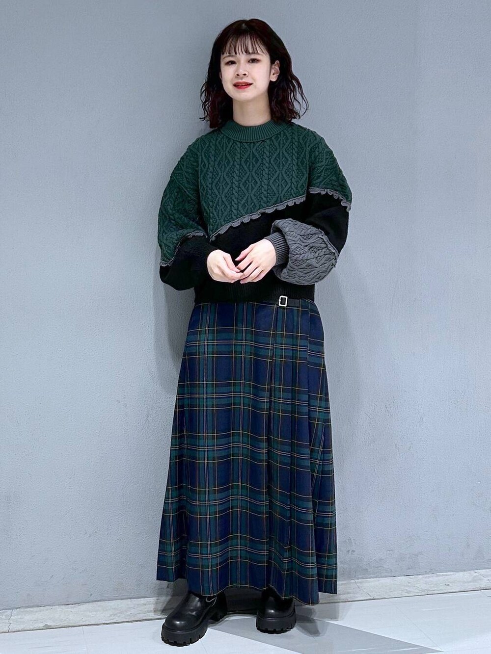 ブラック系のブーツ、グリーン系のスカート、ブラック系のニット/セーターを着用したレディースの秋コーディネートの4枚目の写真