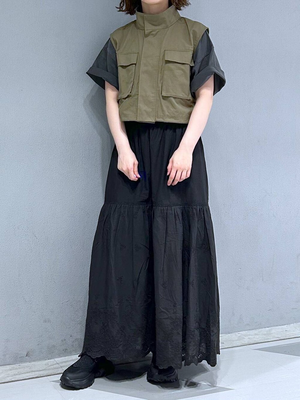 ブラック系のスカート、グリーン系のベスト、ブラック系のTシャツ/カットソーを着用したレディースの夏コーディネートの2枚目の写真