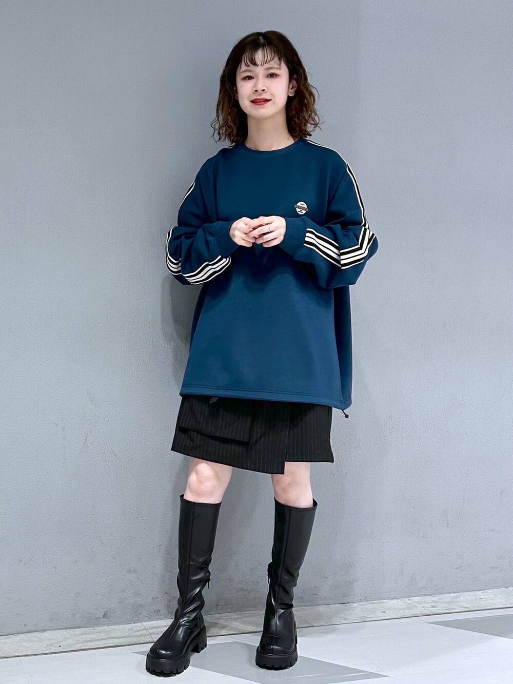 ブラック系のブーツ、ブラック系のスカート、ブルー系のスウェットを着用したレディースの秋コーディネートの4枚目の写真