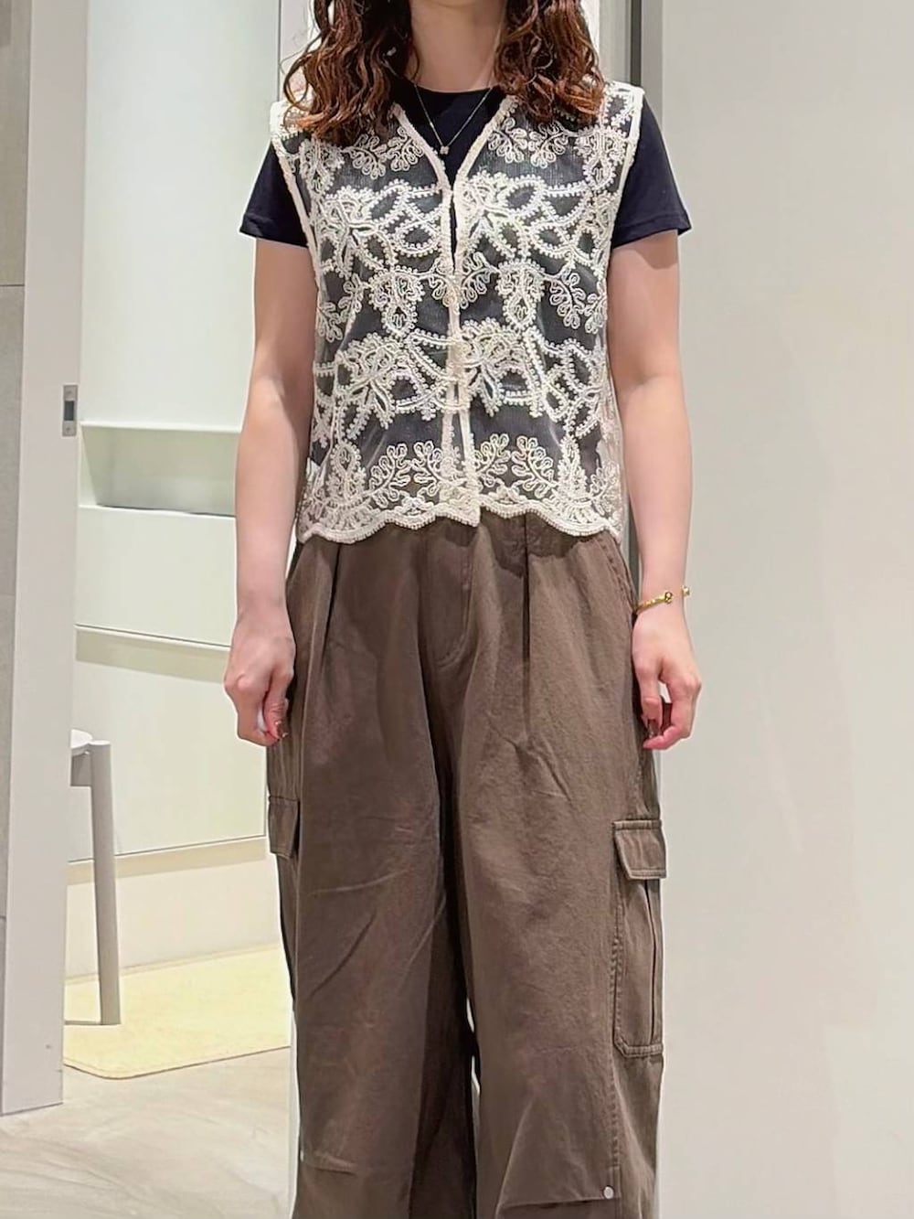 グリーン系のカーゴパンツ、ホワイト系のベスト、ブラック系のローファーを着用したレディースの夏コーディネートの3枚目の写真