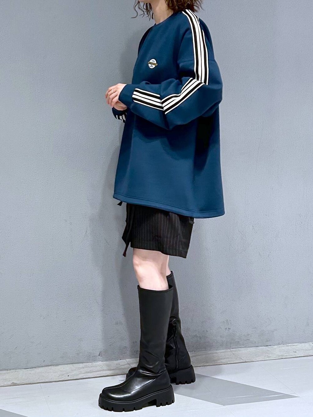 ブラック系のブーツ、ブラック系のスカート、ブルー系のスウェットを着用したレディースの秋コーディネートの3枚目の写真