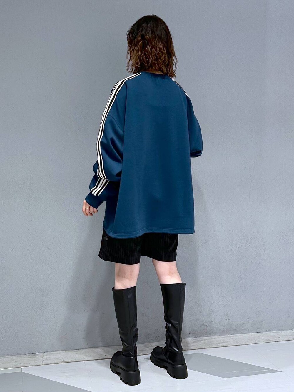 ブラック系のブーツ、ブラック系のスカート、ブルー系のスウェットを着用したレディースの秋コーディネートの5枚目の写真