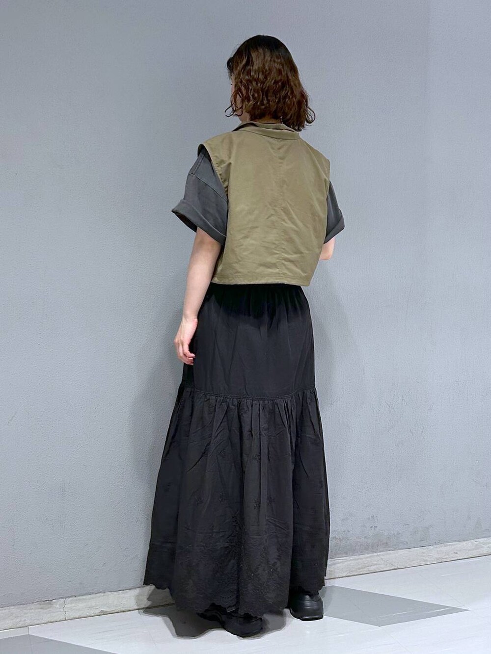 ブラック系のスカート、グリーン系のベスト、ブラック系のTシャツ/カットソーを着用したレディースの夏コーディネートの5枚目の写真