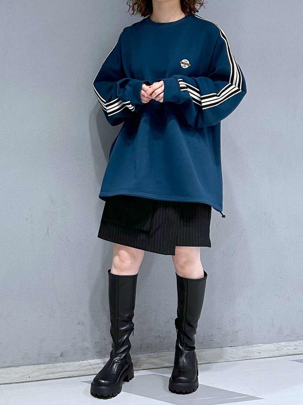 ブラック系のブーツ、ブラック系のスカート、ブルー系のスウェットを着用したレディースの秋コーディネートの2枚目の写真