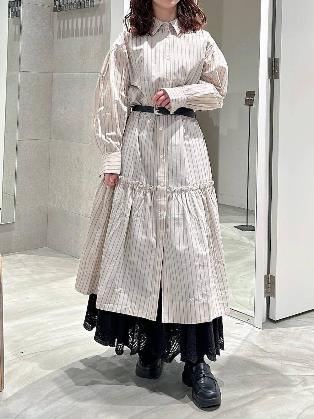 ブラック系のローファー、ベージュ系のシャツワンピース、ブラック系のスカートを着用したレディースの春コーディネートの2枚目の写真