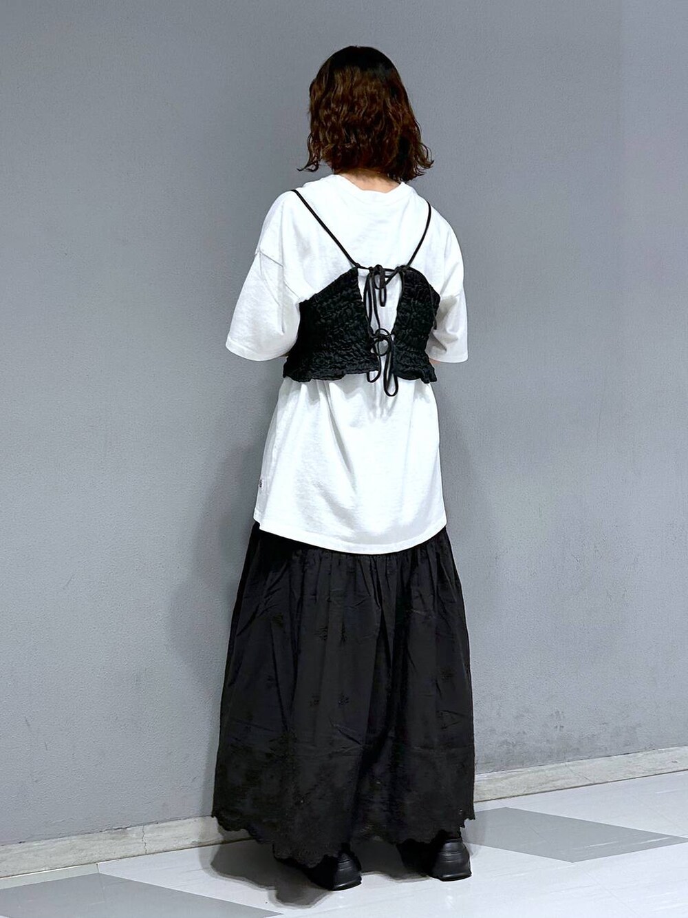 ブラック系のベスト、ホワイト系のTシャツ/カットソー、ブラック系のスカートを着用したレディースの夏コーディネートの4枚目の写真