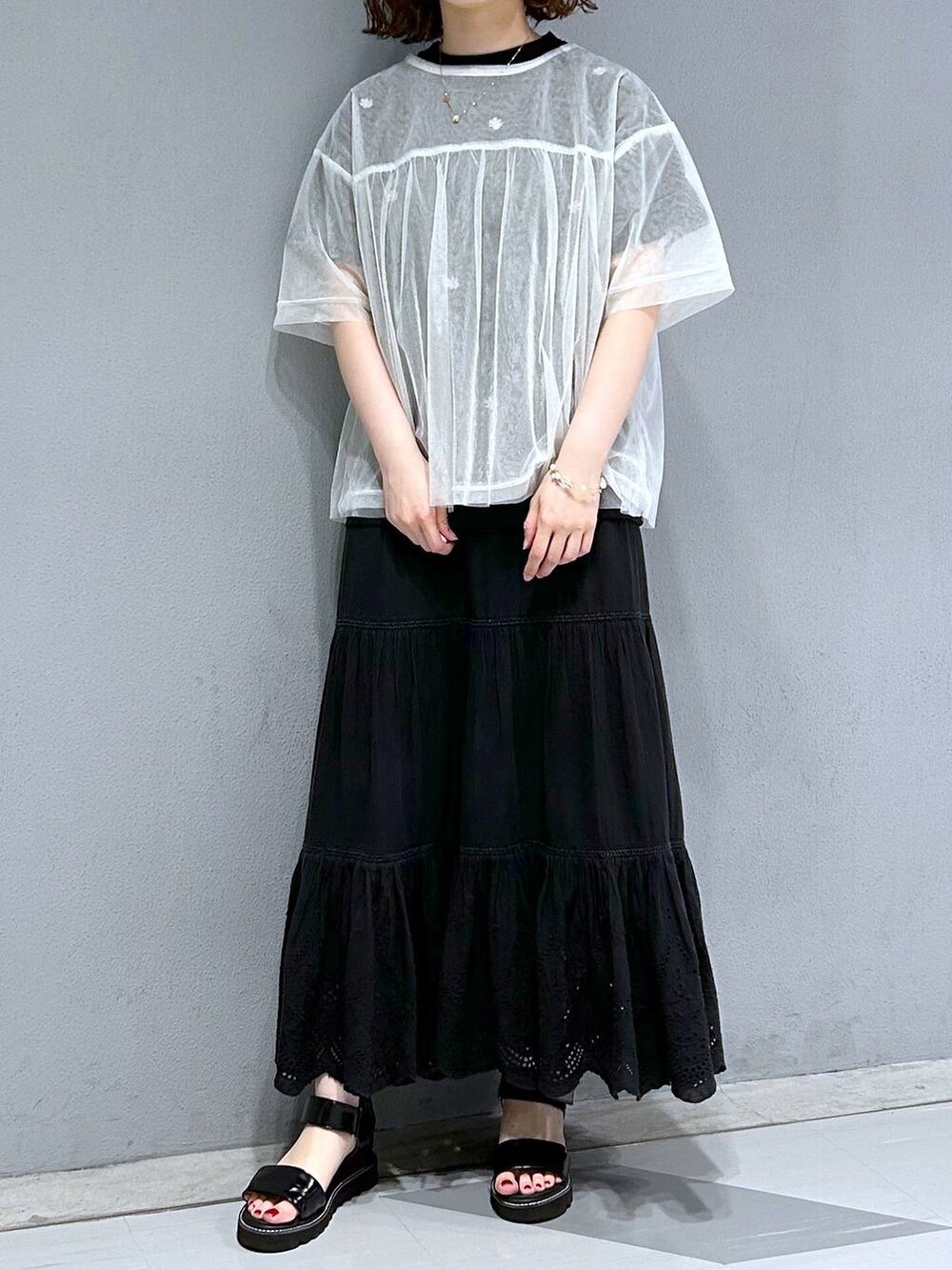 ブラック系のスカート、ホワイト系のTシャツ/カットソー、ブラック系のTシャツ/カットソーを着用したレディースの夏コーディネートの2枚目の写真