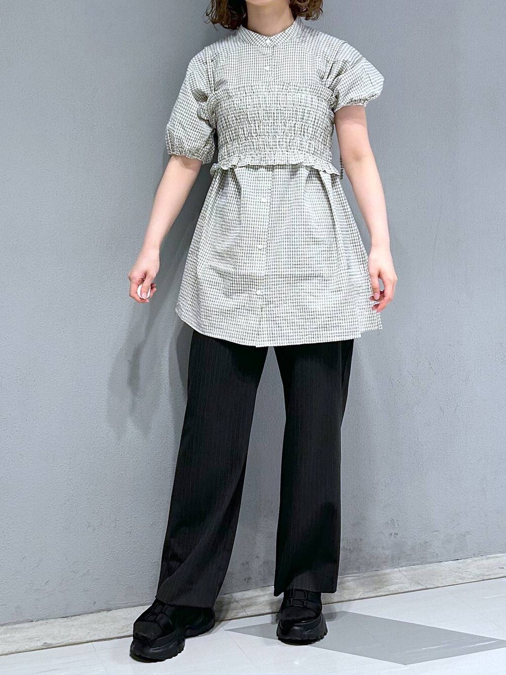 ブラック系のスラックス、ホワイト系のシャツ/ブラウス、ブラック系のサンダルを着用したレディースの夏コーディネートの2枚目の写真