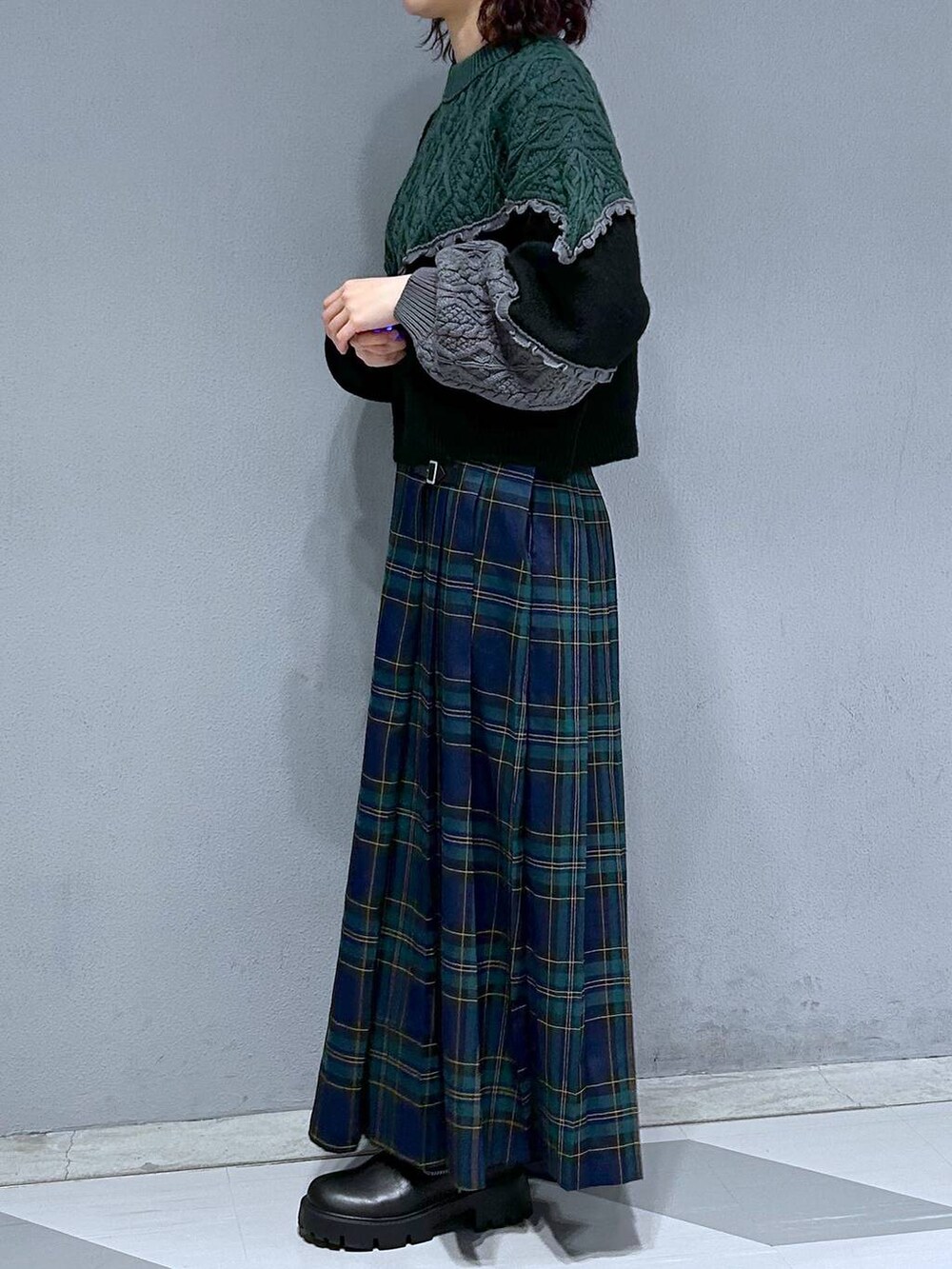 ブラック系のブーツ、グリーン系のスカート、ブラック系のニット/セーターを着用したレディースの秋コーディネートの3枚目の写真