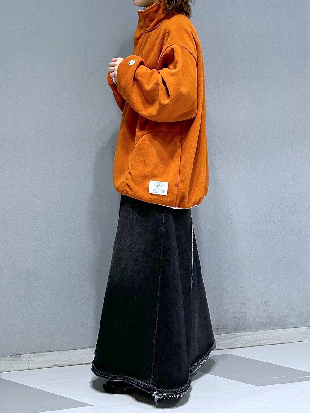 ブラック系のデニムスカート、オレンジ系のスウェットを着用したレディースの秋コーディネートの3枚目の写真