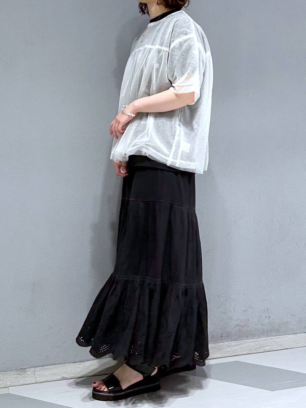ブラック系のスカート、ホワイト系のTシャツ/カットソー、ブラック系のTシャツ/カットソーを着用したレディースの夏コーディネートの3枚目の写真