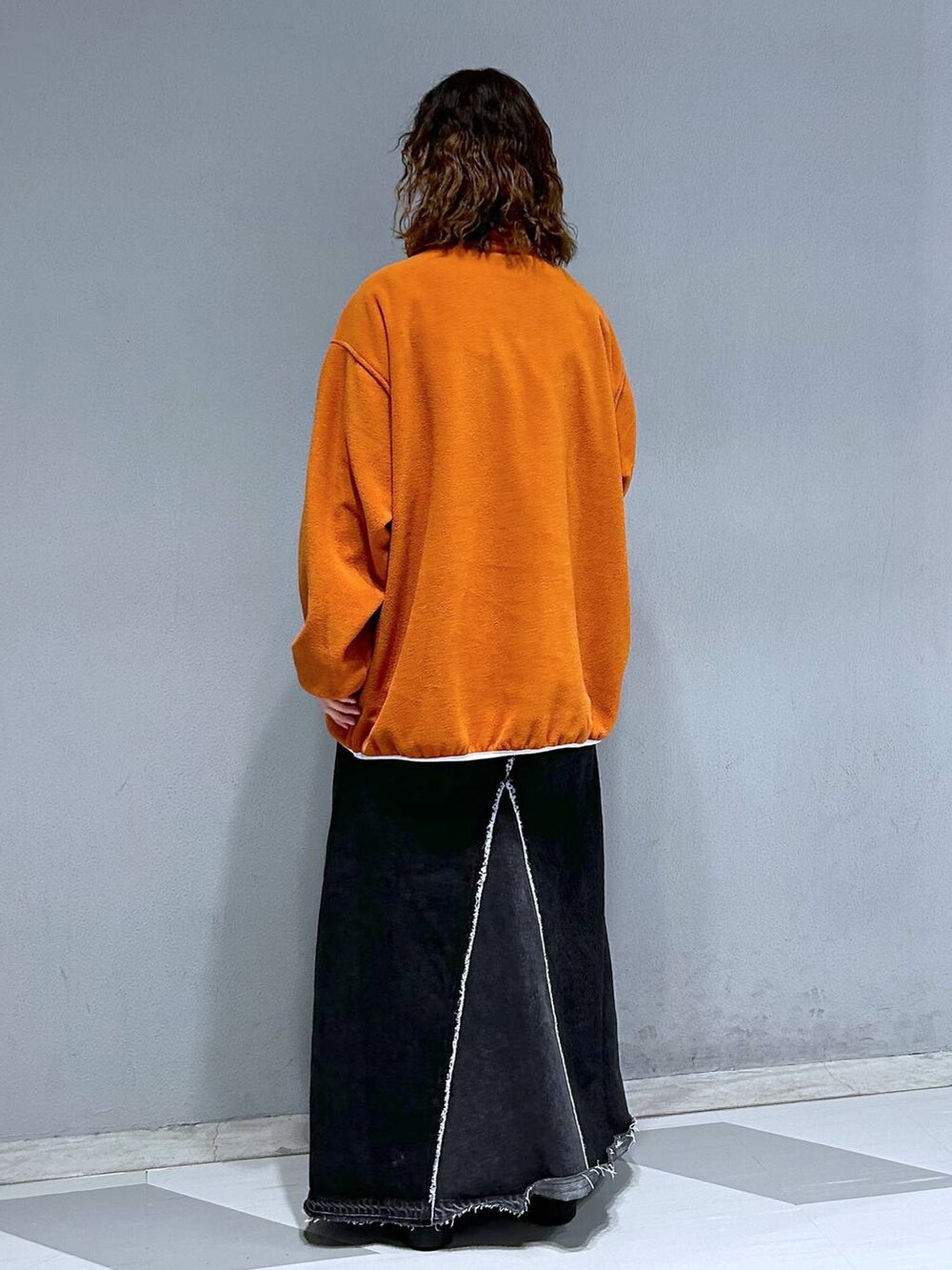 ブラック系のデニムスカート、オレンジ系のスウェットを着用したレディースの秋コーディネートの5枚目の写真