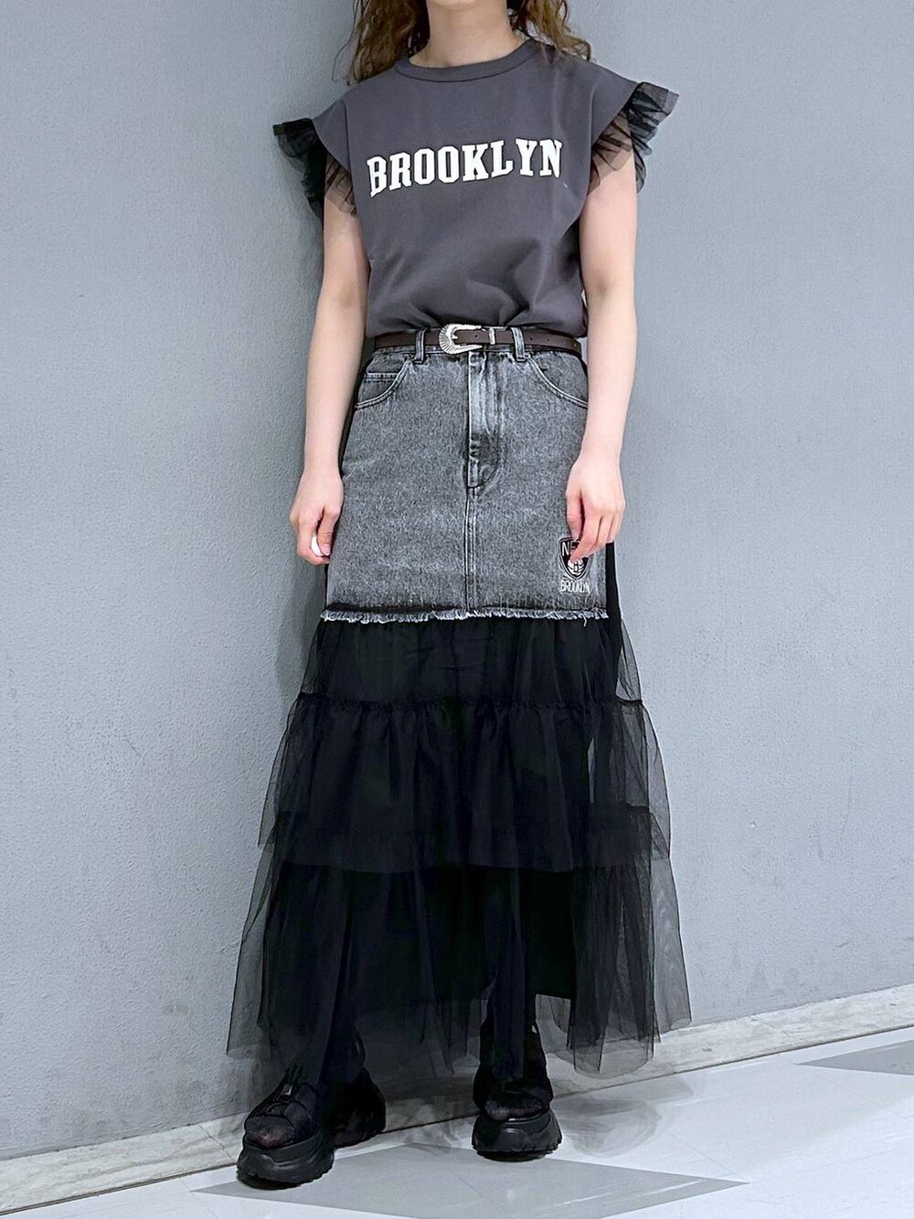 ブラック系のTシャツ/カットソー、ブラック系のデニムスカート、ブラウン系のベルトを着用したレディースの春コーディネートの2枚目の写真