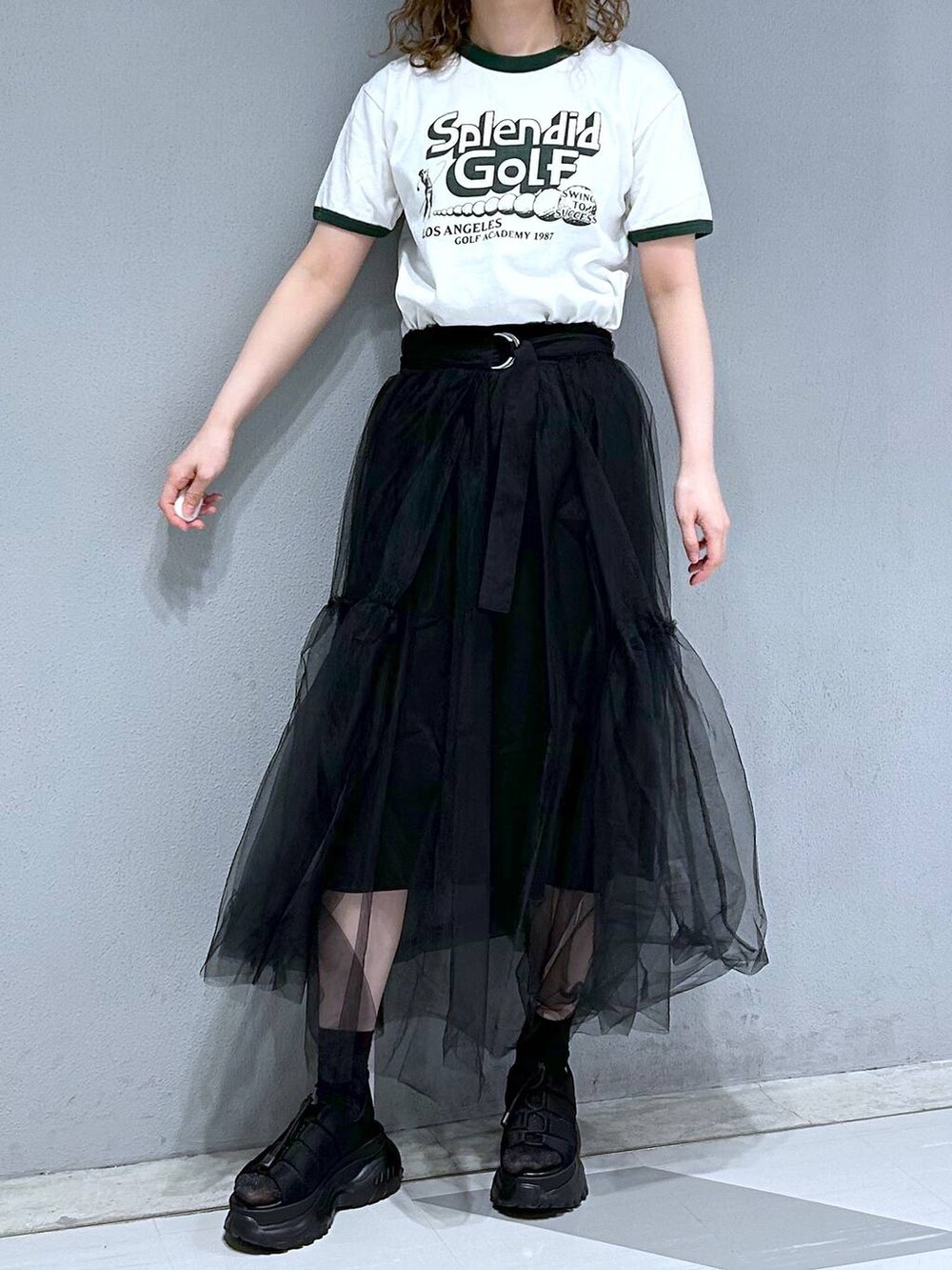 グリーン系のTシャツ/カットソー、ブラック系のスカートを着用したレディースの春コーディネートの2枚目の写真