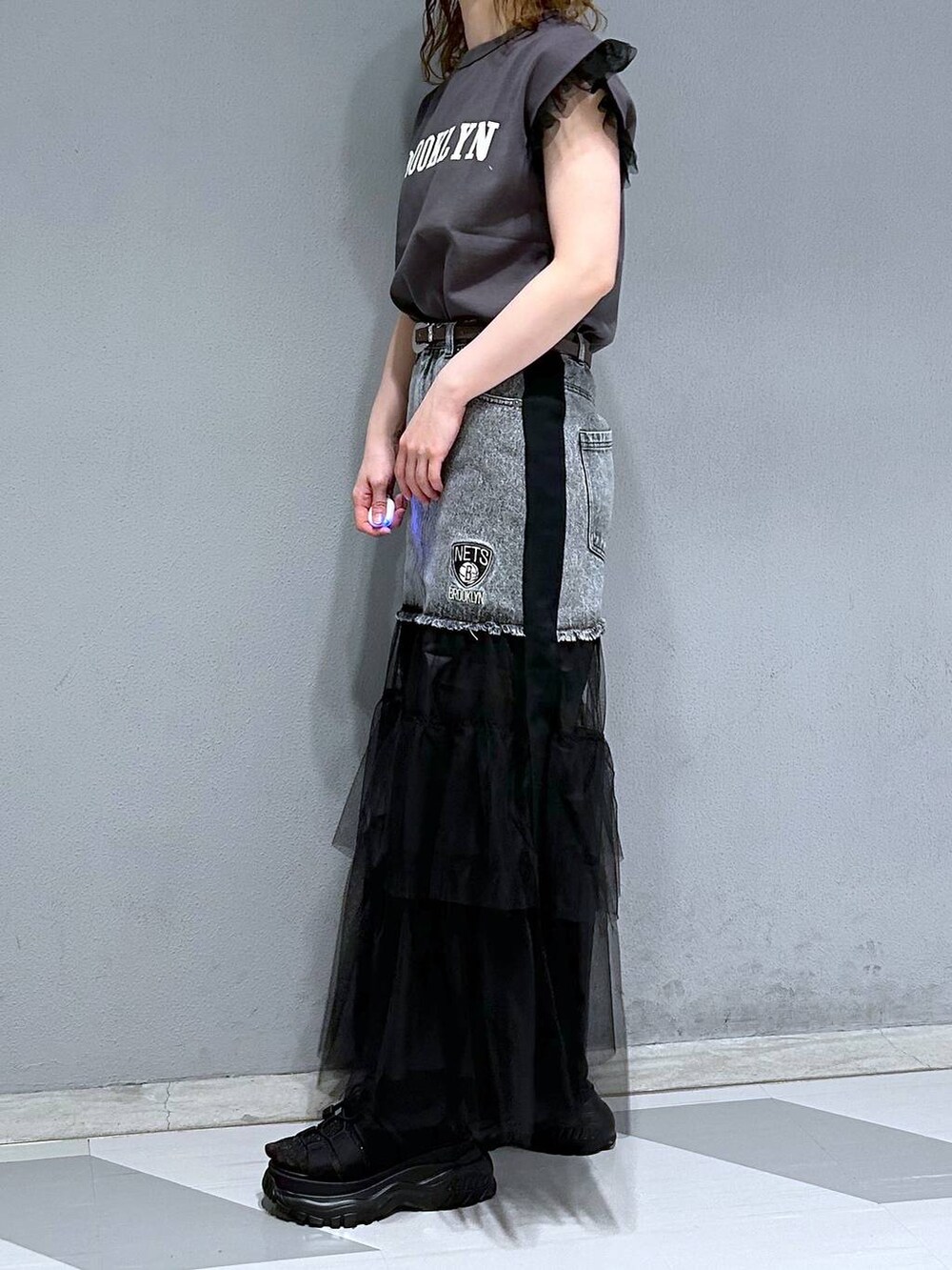 ブラック系のTシャツ/カットソー、ブラック系のデニムスカート、ブラウン系のベルトを着用したレディースの春コーディネートの3枚目の写真